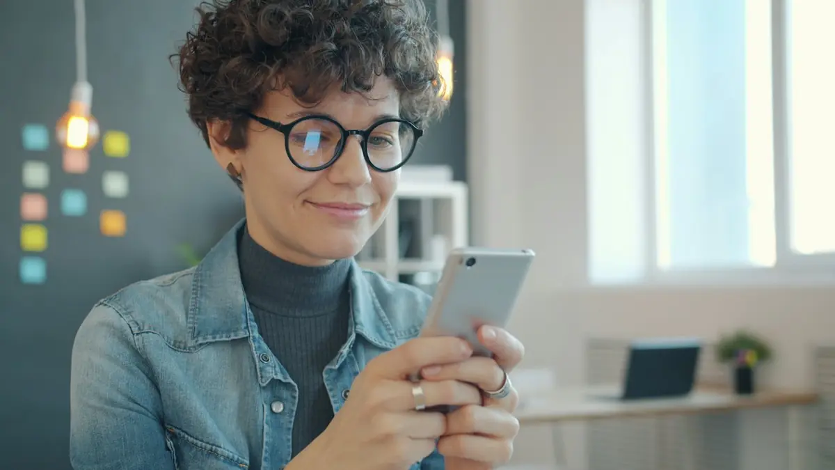 Mujer consultando su móvil en casa